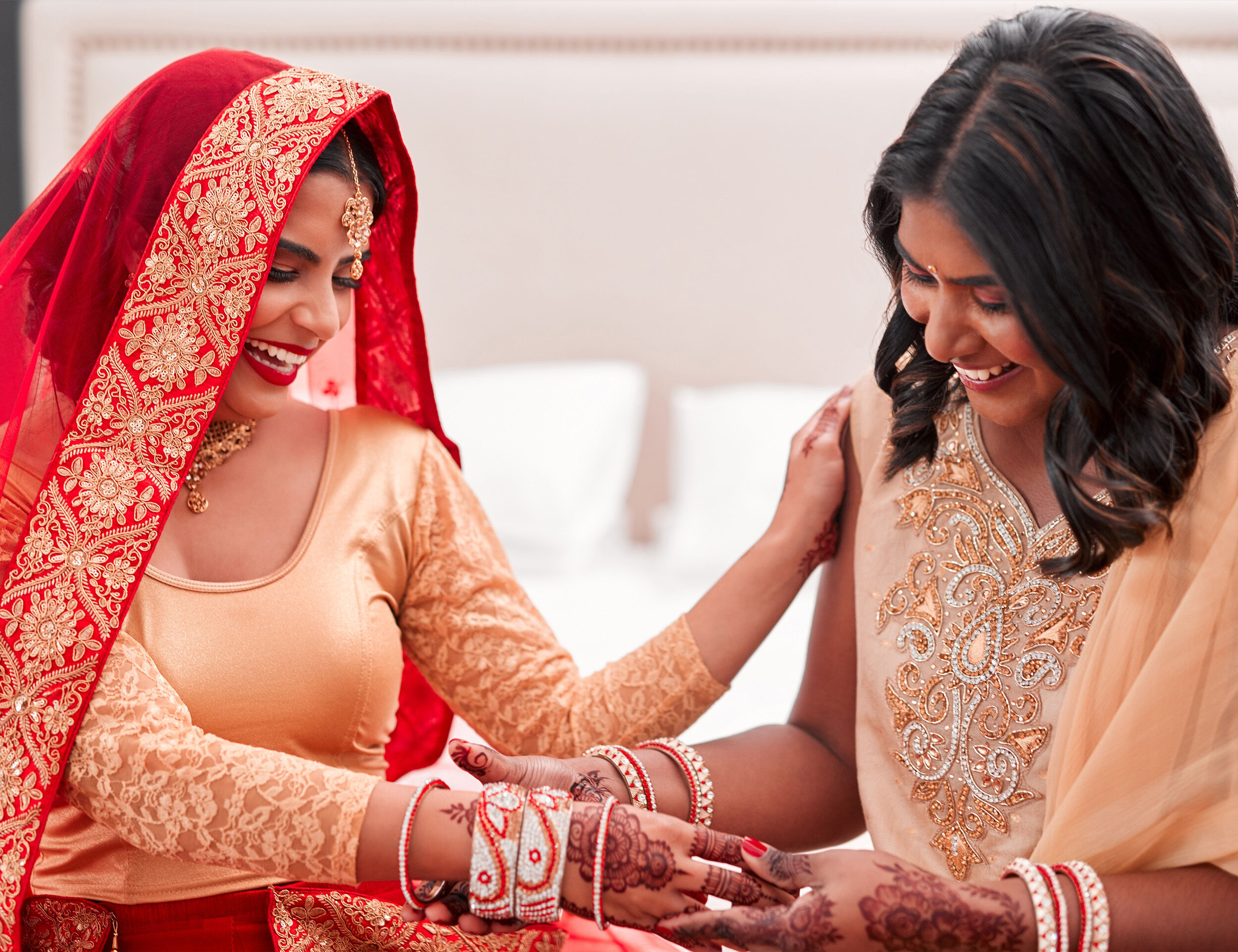 A bridesmade putting bangles on brides hand 